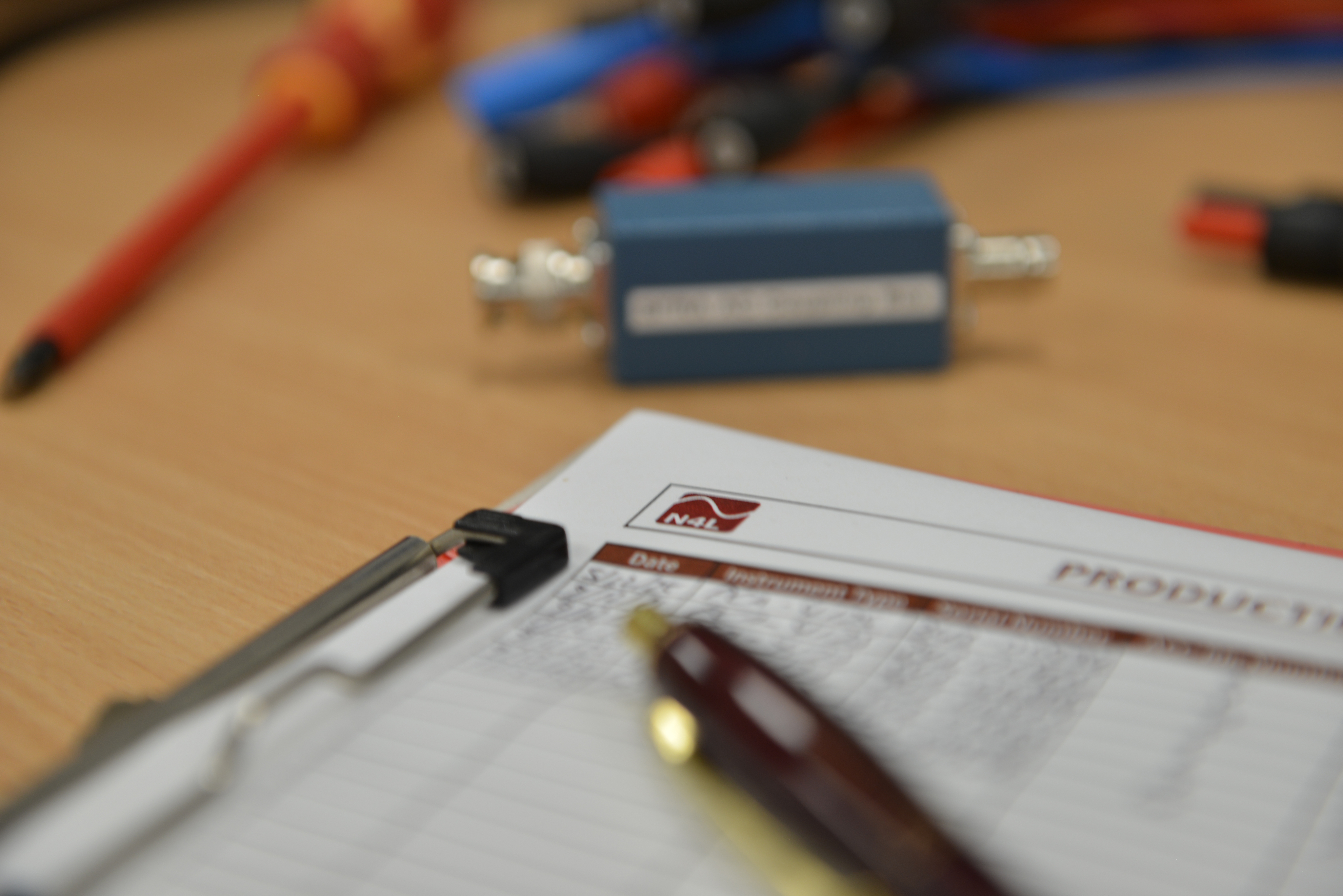 Clipboard on desk contain documentation for design a custom test system.